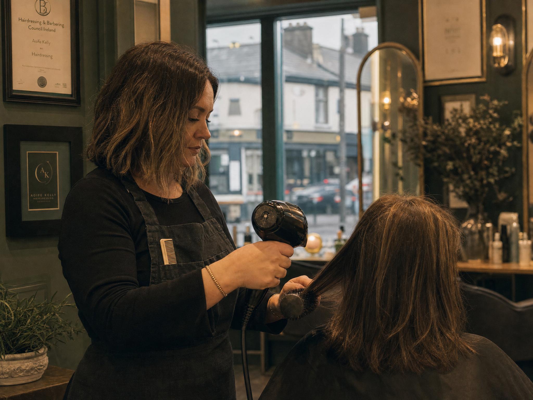 A salon owner on their phone in the shop, checking a review request between clients.